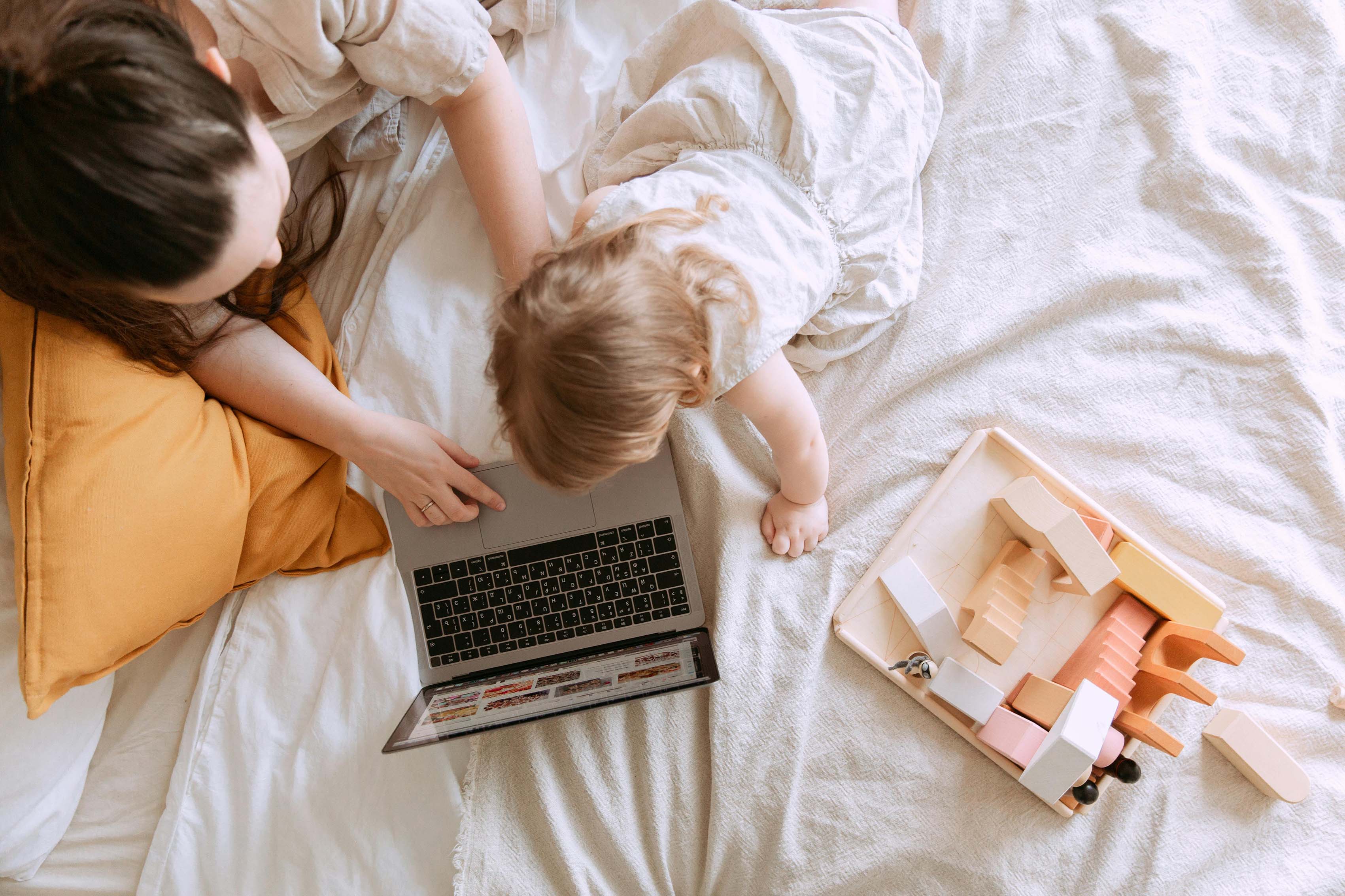 Mother and baby on bed with a laptop and toy blocks - Sonny & Rein - Beautiful keepsakes, custom laser engraving and bespoke gifts for all occasions